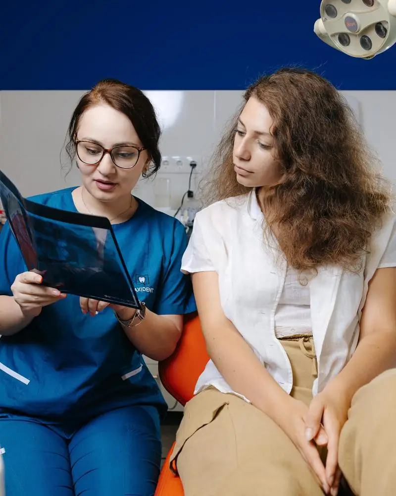 MaxiDent-ის ექიმი პაციენტს სურათს უხსნის